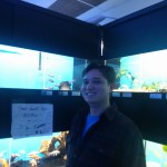 Marketing Specialist Aubrey Nesbitt stands in front of an aquarium