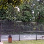 Caged basketball court with bench near mid-rise River Towers condo